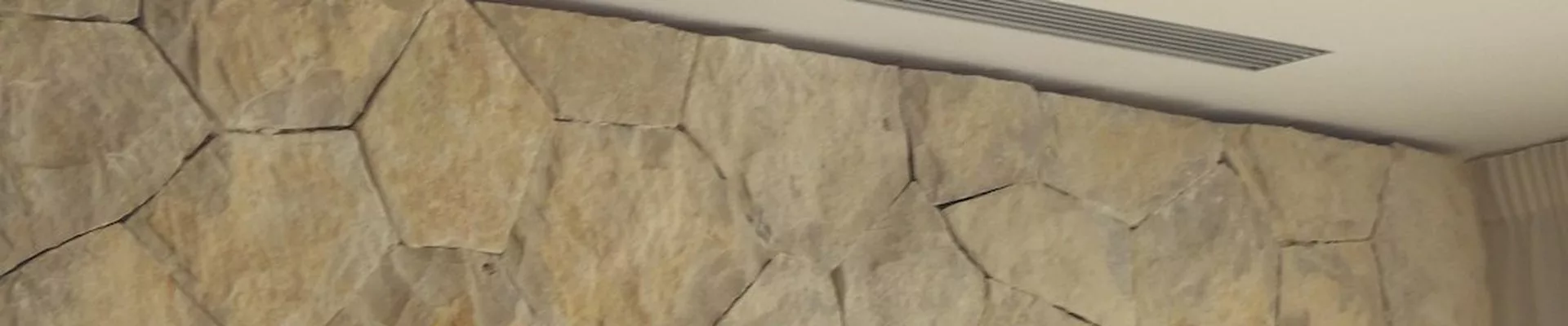 Linearer Luftauslass über einer Natursteinwand